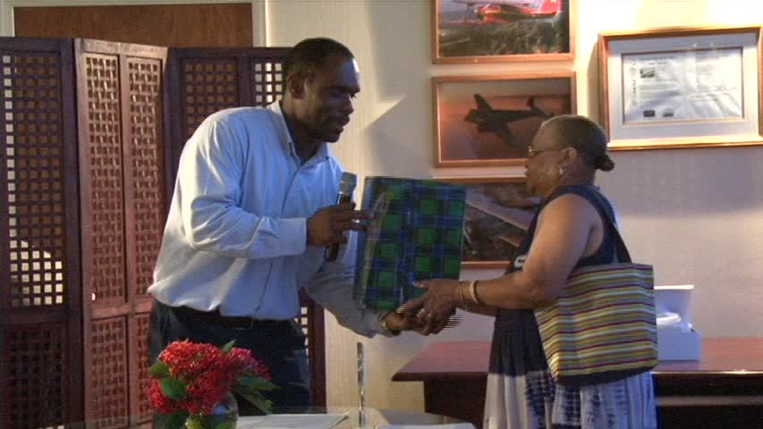 Chairman of the Nevis Air and Sea Ports Authority Mr. Collin Dore presents retiree Ms. Elvira “Fairy” Clarke with a plaque and gift” for her 22 years of service at the Vance W. Amory International Airport on December 30, 2013